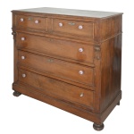 Brasil. Séc. XIX - Cômoda brasileira em madeira nobre, de formato retangular. Tampo liso, bordado por friso saliente, apoiado em caixa reta. Apresenta frente com par de gavetas alinhadas sobre discreta moldura, com 3 gavetões superpostos na parte inferior. Laterais ornadas por colunatas com capiteis esculpidos em alto relevo. Base retilínea apoiada em pés de bolacha. Puxadores em vidro moldados com gomos. 107 x 116 x 63 cm. Falta 1 puxador e 2 espelhos de chave. Sinais de uso e do tempo.