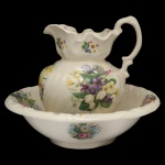 Jarra e bacia em louça inglesa policromada. Fundo de superficie claro com decoração floral. 10 x 37 cm (bacia). 29 x 24 x 22 cm (jarro)