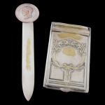 Lote constando de 2 peças em metal prateado, sendo A) CHRISTOFLE - Espátula para abrir correspondência. Apresenta desgastes. 22 x 5 cm. B) WOLFF - Porta papel de formato retangular. Apresenta desgastes. 5 x 9 cm. NO ESTADO.