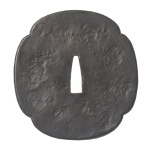 Antiga e raríssima tsuba de grande tamanho, do tipo saotome, em ferro carbono forjado, de formato mokko gata, quadrilobulada, pertencente a um Damyo, no caso o chefe do clã Otomo, das famílias Ietada/Iesada. Apresenta decoração martelada reproduzindo chão de área externa, realçado pela cunhagem de uns 10 ideogramas kanji de cada lado, característica do estilo tembo, incluindo os títulos e o nome do Damyo, estampados repetidamente com caracteres Kanji, tais como Dai, significando grande nome ou grande senhor de terras, Lingtu, território, e Dashi, mestre. Meados do Período Muromachi (1338-1573). Acompanha caixa em madeira.10,0 x 9,5 x 0,5 cm.
