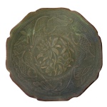 Dinastia Ming (1368-1644). Séc. XVII - Delicado bowl raso em porcelana chinesa, de formato lobulado, com borda ondulada e oitavada. Apresenta coberta celadon do tipo Yaozhou ou celadon do Norte, muito levemente craquelada, e ornamentada por incisos. Margem decorada por carpas e lotus, centralizando medalhão floral. Base baixa e retraída. Dinastia Ming (1368-1644). Séc. XVII. 3,8 x 15,0 cm.