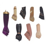 Conjunto de 8 figas de tamanhos e materiais diversos. Algumas apresentam adornos em ouro como unhas ou pulseiras. A maior, de cor roxa, realçada por arremate com argola na extremidade.. 5 cm (maior) / 3 cm (menor).