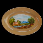 D. JOÃO VI . Serviço Sépia, Verde e Dourado. Séc. XIX -  Travessa em  porcelana possivelmente francesa pertencente ao Serviço Sépia, Verde e Dourado de D. João VI. Apresenta formato oval com uma cena central representando uma casa com árvores e rio ao fundo. Borda com larga faixa em ouro.  20 x 14 cm. Desgaste no dourado. Peça do mesmo serviço reproduzida no Livro Louça da Aristocracia no Brasil de Jenny Dreyfus, à pág. 189.