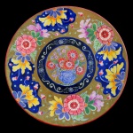 JAPÃO. Séc. XIX - Prato em porcelana oriental apresentando decoração tradicional com flores ao centro e motivos florais nas bordas. Utiliza uma paleta rica com fundo dourado e bege detalhes em azul profundo, vermelho e amarelo. Pequeno restauro na borda. 26 cm.