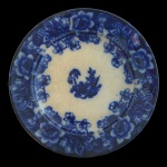 NEW WHARF POTTERY & Co. - England. Flow Blue - Prato em louça inglesa do séc. XIX. Apresenta reserva central com vegetação e borda com decoração floral intensa. Marca da manufatura no verso.