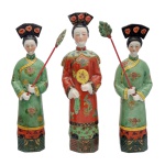 Conjunto de 3 estatuetas em porcelana chinesa policromada, representando dignatária ladeada por atendentes com grandes leques. Exibem trajes formais, ricamente bordados e belos enfeites de cabelos. Bases quadrangulares chanfradas.42 cm / 43 cm / 40 cm.