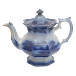 ENGLAND, Séc. XIX. Flow Blue - Bule para chá em louça inglesa. Apresenta decoração em azul cobalto com efeito borrado sobre fundo branco, com cena lacustre em jardim. Pega da tampa em formato de pinha e alça com curvas e contra curvas.  23 x 25 cm.