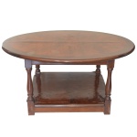 Mesa de apresentação em madeira nobre, com tampo oval e borda canelada. Caixa retangular lisa com pés retos e torneados, ornados por anelados, e apoiados na base sobre plateau inferior alto com borda retilínea e pequenos pés. 52 x 110 x 80 cm. Tampo com manchas e folha solta. No estado.