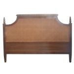 Cabeceira de cama de casal em madeira nobre, de formato retangular. Parte superior forrada em palhinha da Índia, com quinas recortadas e ornadas por ponteiras, centralizando frontão reto e liso. Pernas curtas e retilíneas. 125 x 172 cm.