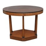 Mesa lateral ou mesa de apoio em madeira nobre com características que remetem ao estilo Império. Tampo de formato oval com superficie plana, sustentado por quatro colunas e que se conectam a uma base sólida  Séc. XX. 78 x 96 x 65 cm.