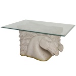 Mesa lateral com base esculpida em pedra natural na forma de cabeça de cavalo, sustentando um tampo de vidro. 44 x 80 x 65 cm.