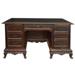 Mesa de escritório em madeira nobre, de formato retangular, profusamente esculpida e ornada com almofadas, frisos florais e faixas estilizadas. Tampo liso com borda canelada e saliente, apoiada em caixa reta, apresentando gavetão ladeado por 3 gavetas superpostas. Verso com fundo fechado e saia recortada. Base reta e lavrada em arcos, apoiada em montantes ondulados rematados nas extremidades por pares de pés revirados em volutas. 82 x 154 x 80 cm. Este lote encontra-se na casa do comitente no Alto da Boa Vista, SP. A retirada deverá ser agendado previamente com o nosso escritório no telefone 11.5044.1228.