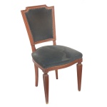 Cadeira com estrutura em madeira clara e lisa, ornada por frisos canelados. Encosto com montantes retos levemente inclinados, rematado por cachaço com quinas recortadas. Assento abaulado à frente, apoiado em saia lisa com bordas filetadas. Pernas dianteiras no formato de colunas retas, de secção quadrangular. Forração tacheada de cor escuro  90 x 48 x 47 cm