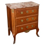 Pequena meia cômoda em madeira nobre, estilo Louis XV, ornada em parqueterie com frisos e filetes, realçada por adornos em bronze dourado. Tampo retangular em mármore rajado chanfrado à frente, apoiado em caixa reta. Apresenta 3 gavetões superpostos ladeados por quinas bisotadas, apoiadas em pernas dianteiras arqueadas com joelhos salientes e pés recamados por folhagens. Saia reta centralizando adorno floral.