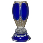 Copo em grosso cristal transparente da Boêmia, com laterais levemente arqueadas, revestido e ornado por overlay de cor azul. Apresenta bordas lapidadas com anelados. Base apoiada em pé circular, acompanhando o estilo com friso inferior dentado 13 cm.