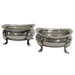 par de saleiros em metal espessurado a prata inglesa com corpo liso sobre 4 pés altos, medindo 6x3x4,5cm.