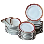 Aparelho de jantar em porcelana polonesa da manufatura Jarolina com faixa no tom de vermelho com apicação a ouro retratando folhas composto por 15 pratos rasos, 11 pratos fundos, 12 pratos de sobremesa e 3 travessas, medindo os rasos 24,5cm de diâmetro, os fundos 24cm de diâmetro, os de sobremesa 20cm de diâmetro e as travessas 29cm e 25cm de comprimento respectivamente. Marcas de uso. 