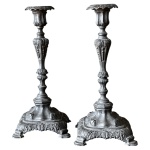 Par de castiçais ao estilo portugues em estanho com trabalho característico das peças ao estilo Dom José, bases quadradas e corpos alongados finamente cinzelados medindo 30cm de altura e 14cm de largura. 