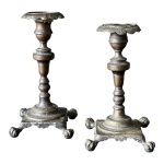 Par de castiçais ao estilo portugues em metal prateado com trabalho característico das peças portuguesas, bases quadradas com pés em garra e corpos alongados finamente cinzelados medindo 20cm de altura e 10cm de largura. 