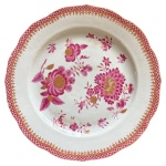 Prato em porcelana chinesa do século XVIII companhia das índias no padrão família rosa com pintura retratando grandes flores e borda rendillhada em rosa e decoração a ouro, medindo 23cm de diâmetro. Pequenos bicados. 