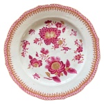 Prato em porcelana chinesa do século XVIII companhia das índias no padrão família rosa com pintura retratando grandes flores e borda rendillhada em rosa e decoração a ouro, medindo 23cm de diâmetro. Pequenos bicados. 