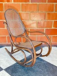 MOBILIÁRIO - CADEIRA DE BALANÇO THONET EM MADEIRA CURVADA  ESTILO VIENENSEIcônica cadeira de balanço em madeira curvada ao vapor, modelo atribuído à escola de design vienense do século XIX, inspirado nos clássicos de Michael Thonet. Estrutura elegante com curvas sinuosas e acabamento escuro, encosto e assento em palhinha natural tramada. Peça leve, resistente e de grande apelo estético, ideal para compor ambientes com charme retrô ou vintage.Em bom estado estrutural, com leve pátina do tempo. Med. 102x54x110 cm.