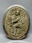 BRONZE - Antiga e expressiva placa decorativa em bronze, espessurada a níquel, representando figura infantil em meio à natureza, ricamente trabalhada em alto-relevo. A cena apresenta delicadas flores, folhagens e fundo texturizado, conferindo movimento e profundidade à composição. Peça de grande presença estética e qualidade escultórica.Med. 31x25 cm.