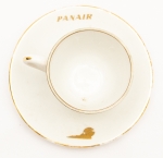 Colecionismo - Aviação - Conjunto Xícara e Pires da extinta Cia Aérea PANAIR, em porcelana na cor branca, decorada com friso dourado junto à borda e na alça de ambas as peças. Logomarca e logotipo na cor dourada em lados opostos das peças. Inscrições nos fundos da xícara e do pires: "Porcelana Schmidt. S. Catarina. Made in Brazil".