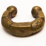 Numismática, Ogondo ou manila. Moeda de troca e adorno de origem africana. Possui o formato de pulseira. Muito colecionável, com grande procura no mercado numismático internacional e também como peça exótica. No Brasil já existem recentes publicações à respeito. Exemplar proveniente de coleções europeias de mais de 50 anos de garimpo. Robusto exemplar muito trabalhado em tribais. 90x90mm. 65g. Certamente peça de importante membro. Acreditamos século XVIII - início XIX.  