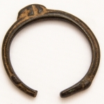 Numismática, Ogondo ou manila. Moeda de troca e adorno de origem africana. Possui o formato de pulseira. Muito colecionável, com grande procura no mercado numismático internacional e também como peça exótica. No Brasil já existem recentes publicações à respeito. Exemplar proveniente de coleções europeias de mais de 50 anos de garimpo. Raríssimo exemplar com detalhes nas pontas e animal na parte superior. Preserva vestígios do solo onde foi encontrado. Exemplar inédito. 5,5x5,6cm. Possivelmente de criança. 25g. 