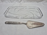 Prato de rocambole em vidro moldado com espátula em metal prateado. Medindo 31,5cm x 16cm.