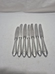 Jogo de 7 facas em aço inox Wolff, modelo rosinha, sendo 6 de mesa e 1 de sobremesa. Medindo as de mesa 23cm e a de sobremesa 20cm. Laminas arranhadas.