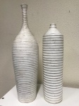 Lindo par de vasos decorativos de chão, na cor branco, com um design moderno e elegante, ideais para adicionar um toque artístico a qualquer ambiente, forma de garrafa com um padrão canelado (nervurado) distinto, conferindo-lhes uma textura e sofisticação únicas. Medem: 45x13 e 36x10.