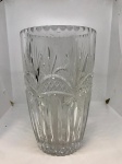 elegante vaso de vidro transparente, com um design clássico e atemporal, é perfeito para adicionar um toque de sofisticação a qualquer ambiente. A sua superfície é ricamente adornada com lapidação detalhada, apresentando padrões geométricos e em forma de folha que refletem a luz de maneira deslumbrante, criando um jogo de brilho e profundidade.  Mede: 25x15.