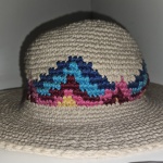 Lindo chapéu de praia feito de crochê, cor bege com detalhes coloridos. No estado.