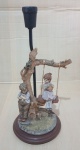 BASE PARA ABAJUR EM METAL - COM ESCULTURA EM RESINA MENINO E MENINA NO BALANÇO 39 X 5 X 18 CM - BASE EM MADEIRA.