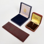 COLECIONISMO, três (3) itens: 1 estojo vazio para a serie de moedas brasileiras AXE; 1 alfinete em metal dourado, esmaltado com a bandeira do Brasil, acondicionado em caixa adaptada da KRAUSE; 1 caixa vazia para medalha, vide foto.