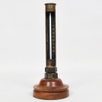 DIVERSOS, um (1) antigo termômetro, acoplado em cilindro metálico, base em madeira torneada, sem marca de manufatura aparente, sinais de uso, vide foto.