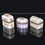 PORCELANA, três (3) caixas miniaturas, ornamentação floral policromada, arremates a ouro, monture em bronze, uma delas com dobradiça partida, medindo a maior 5 x 4 x 3,5 cm, marca de manufatura na base, vide foto, ideais para coleção de cristaleira.