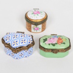 PORCELANA, três (3) caixas miniatura, todas com monture em bronze e ornamentação floral policromada, em uma delas estilizada, 2 da marca PORCELAIN ART; 1 sem marca aparente, medindo a maior 5,5 x 3,5 x 3,5 cm, vide foto.