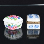 PORCELANA, duas (2) caixas miniatura: 1 ornada com flores em policromia, marca de atelier não identificado no fundo, medindo 5,5 x 4 x 3,5 cm; 1 com monture em bronze, ornada em caracteres orientais, possui craquejado, marca PORCELAIN ART na base, medindo 4 x 4 x 3,5 cm, vide foto.