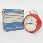 RELÓGIO, um (1) despertador da marca HERWEG (Caixa Postal 14, Timbó, SC), tonalidade vermelha, mecanismo a corda, funcionando com segundeiro parado, demanda revisão, acondicionado na caixa original, sinais de uso, vide foto.