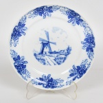 PORCELANA, um (1) prato ornado com paisagem holandesa representando moinho, borda em flores, tonalidade azul sobre fundo branco, manufatura SCHMIDT (Pomerode, SC; Mauá, SP; Campo Largo, PR, fundada em 1945, ainda em atividade, maior fábrica de porcelana da América Latina), medindo 17 cm diâmetro, vide foto.