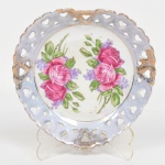 PORCELANA, um (1) prato decorativo quase triangular, borda vazada, ornamentação floral policromada, arremates a ouro já com sinais de desgastes, medindo aproximadamente 14,5 cm diâmetro, sem marca de manufatura aparente, vide foto.