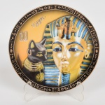 PORCELANA EGÍPCIA, um (1) prato decorativo com ornamentação policromada representando TUTANCÂMON, arremates a ouro, marca FM (Fathy Mahmoud), medindo 16 cm diâmetro, vide foto.