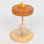 DIVERSOS, um (1) pote de mel com recipiente em vidro, incolor e translúcido, modelagem octogonal, base em madeira torneada, tampa em folha de flandres com adorno representando abelha, medindo 13 cm altura, não aparenta ter sido usado, vide foto.