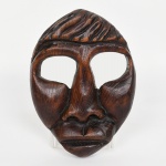 ARTE TRIBAL AFRICANA (possivelmente), uma (1) máscara entalhada em madeira, medindo 23,5 cm altura, assinatura parcialmente legível em cavo no verso, vide foto.