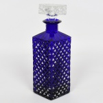 VIDRO, uma (1) licoreira retangular, modelagem em bico de jaca e caneluras, translúcida, tonalidade azul, tampa incolor na mesma padronização, sinais de uso, vide foto, medindo 25 cm altura.