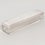 VIDRO, uma (1) antiga caixa retangular para toucador, incolor e translúcida, tampa em metal prateado com borda canelada na horizontal, sem marca de manufatura aparente, medindo 19,5 x 5 x 4,5 cm, sinais de uso, vide foto.