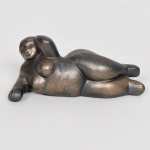 ESCULTURA, uma (1) figurativa representando Mulher Nua, baseada na obra de Fernando Botero (1932 a 2023, pintor e escultor Colombiano), souvenir de Bogotá, confeccionada em material ignorado na tonalidade bronze, medindo 15 cm comprimento, vide foto.